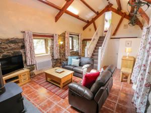 Una sala de estar con un sofá y un televisor. en Melin Bach, en Llanfihangel-y-pennant
