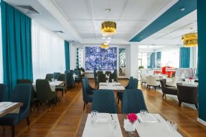 a dining room with tables and chairs and blue curtains at Beluga Hotel in Atyrau
