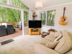 a living room with a couch and a flat screen tv at Willow Lodge in Windermere