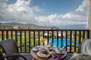 a table with food and drinks on a balcony with a view at Skopelos Holidays Hotel & Spa in Skopelos Town