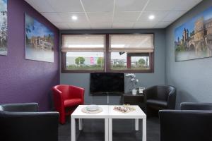 - une salle d'attente avec une table, des chaises et une télévision dans l'établissement HOTEL EDEN - Metz Nord, à Woippy