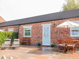 a brick building with a patio with chairs and an umbrella at The Croft in Ashbourne