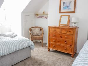 a bedroom with a dresser and a mirror and a chair at Daisy Cottage in Moffat