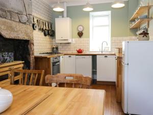 cocina con mesa y nevera en Daisy Cottage, en Moffat