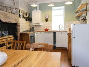 a kitchen with a table and a refrigerator at Daisy Cottage in Moffat