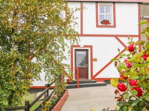 une maison blanche avec une porte rouge et quelques fleurs dans l'établissement Granny Aggie’s Parlour, à Maddan