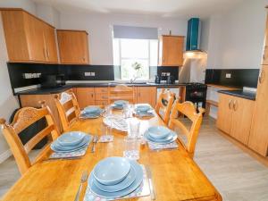 a kitchen with a wooden table with blue dishes on it at Granny Aggie’s Parlour in Maddan