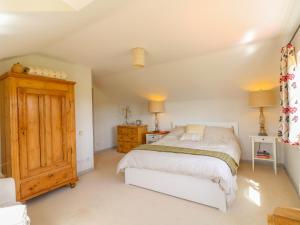een slaapkamer met een bed en een houten kast bij Grooms Cottage in Leicester