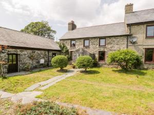 an old stone house with a yard in front of it at Melin Bach in Llanfihangel-y-pennant