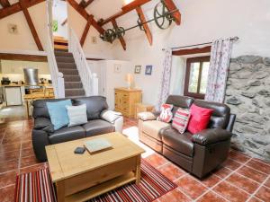 a living room with two leather couches and a table at Melin Bach in Llanfihangel-y-pennant