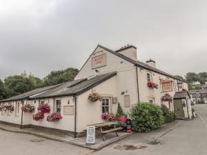 a white building with flowers and a bench in front of it at Dove Cottage in Abergele