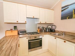 a kitchen with white cabinets and a stove top oven at Willow Lodge in Windermere