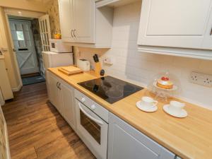 a kitchen with white cabinets and a counter top at Pheasant Cottage in Whitby