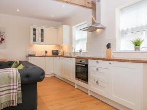 a kitchen with white cabinets and a black couch at The Croft in Ashbourne