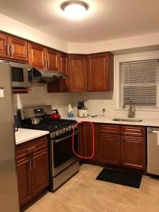 a kitchen with wooden cabinets and a stove with a red hose at 纽约ZUHUA长岛(Hofstra University) （霍夫斯特拉大学）民宿！ in Hempstead