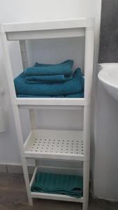 a bathroom with three towels on a shelf next to a sink at Duplex à 5 min aéroport Orly - 15 min Paris in Athis-Mons