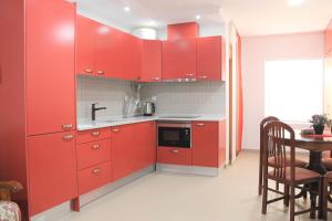 eine rote Küche mit einem Waschbecken und einem Tisch in der Unterkunft Apart Baía do Sado I in Setúbal