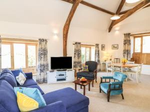 a living room with a blue couch and chairs and a tv at The Old Smithy in Honiton