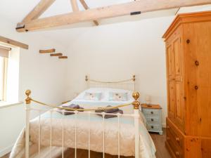 a bedroom with a white bed and a wooden cabinet at The Stables in East Dereham