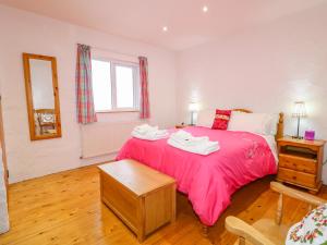 a bedroom with a bed with a red blanket and a table at Quiet Waters Cottage in Coleraine