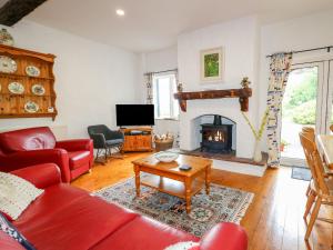 a living room with a red couch and a fireplace at Quiet Waters Cottage in Coleraine