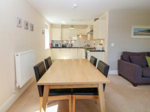a dining room table with chairs and a kitchen at Tirionfa in Llangefni