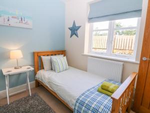 a small bedroom with a bed and a window at Tirionfa in Llangefni