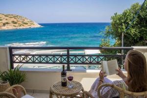 una donna che legge un libro su un balcone con l'oceano di VILLA AKTI a Mochlos