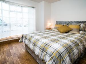 ein Schlafzimmer mit einem Bett mit einer karierten Decke und einem Fenster in der Unterkunft The Captain's Bank in Porthmadog