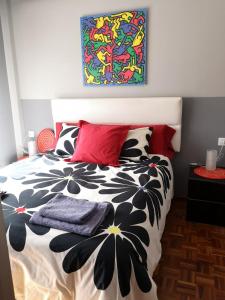 a bedroom with a black and white bed with red pillows at Ático con terraza céntrico Oviedo in Oviedo