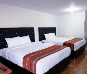 库斯科Hostal Cusco de mis Sueños的酒店房间里有两张床，铺着白色床单
