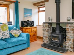 a living room with a blue couch and a wood stove at The Shippon in Barnstaple