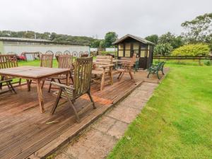 una terrazza in legno con tavolo da picnic e gazebo di The Lodge a Milford Haven