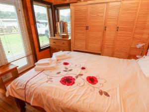 una camera da letto con un letto bianco con fiori rossi di The Lodge a Milford Haven