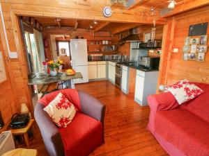 un soggiorno con divano rosso e una cucina di The Lodge a Milford Haven