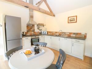 a kitchen with a table and chairs and a refrigerator at The Granary in East Dereham