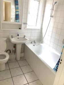 La salle de bains est pourvue d'un lavabo, d'une baignoire et de toilettes. dans l'établissement AC Lounge 115, à Rochford