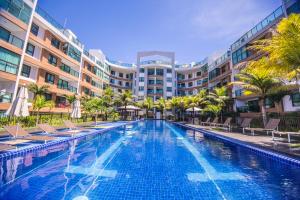 a swimming pool with chairs and palm trees and buildings at Luxor Paulo Miranda Home Service in João Pessoa