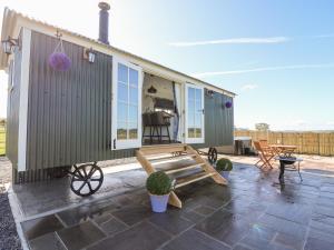 a tiny house with a patio and a table at Cwt Y Gors in Ystrad Meurig