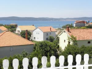 a white fence in front of houses and the water at Apartments Zvone - 100 m from sea in Bibinje
