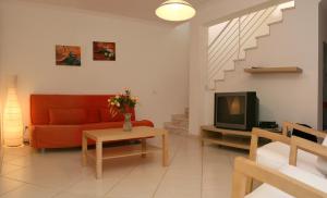 a living room with a red couch and a tv at Villas Oceano in Albufeira