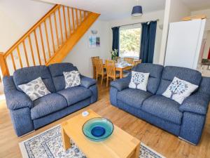 uma sala de estar com dois sofás azuis e uma mesa em Little Freestone em Kilgetty