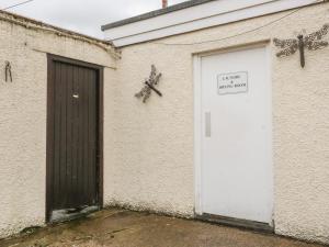 een wit gebouw met een deur en een bord erop bij Mews Studio Cottage 5 in Keswick
