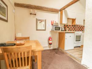een keuken met een houten tafel en een keuken met een magnetron bij Mews Studio Cottage 5 in Keswick