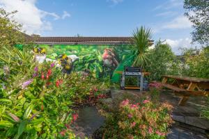 a mural on a wall in a garden with flowers at Doorly Park in Sligo