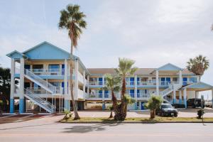 a large building with palm trees in front of it at Scottish Inn & Suites - Kemah Boardwalk in Kemah