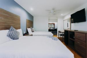 a hotel room with two beds and a flat screen tv at Scottish Inn & Suites - Kemah Boardwalk in Kemah