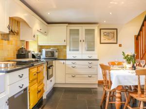 uma cozinha com armários brancos e uma mesa de jantar em Great Bradley Cottage em Minehead