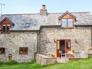 un vecchio cottage in pietra con una porta e finestre rosse di Great Bradley Cottage a Minehead
