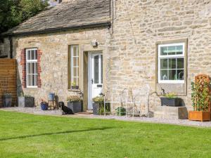 a cat sitting in front of a stone house at Glebe Cottage in Skipton